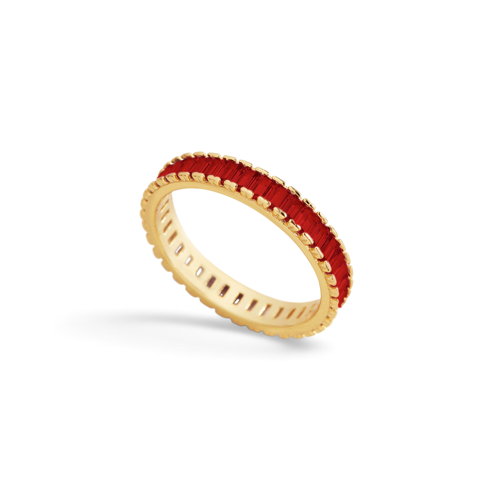 Gold ring with red gemstone on a light gray background