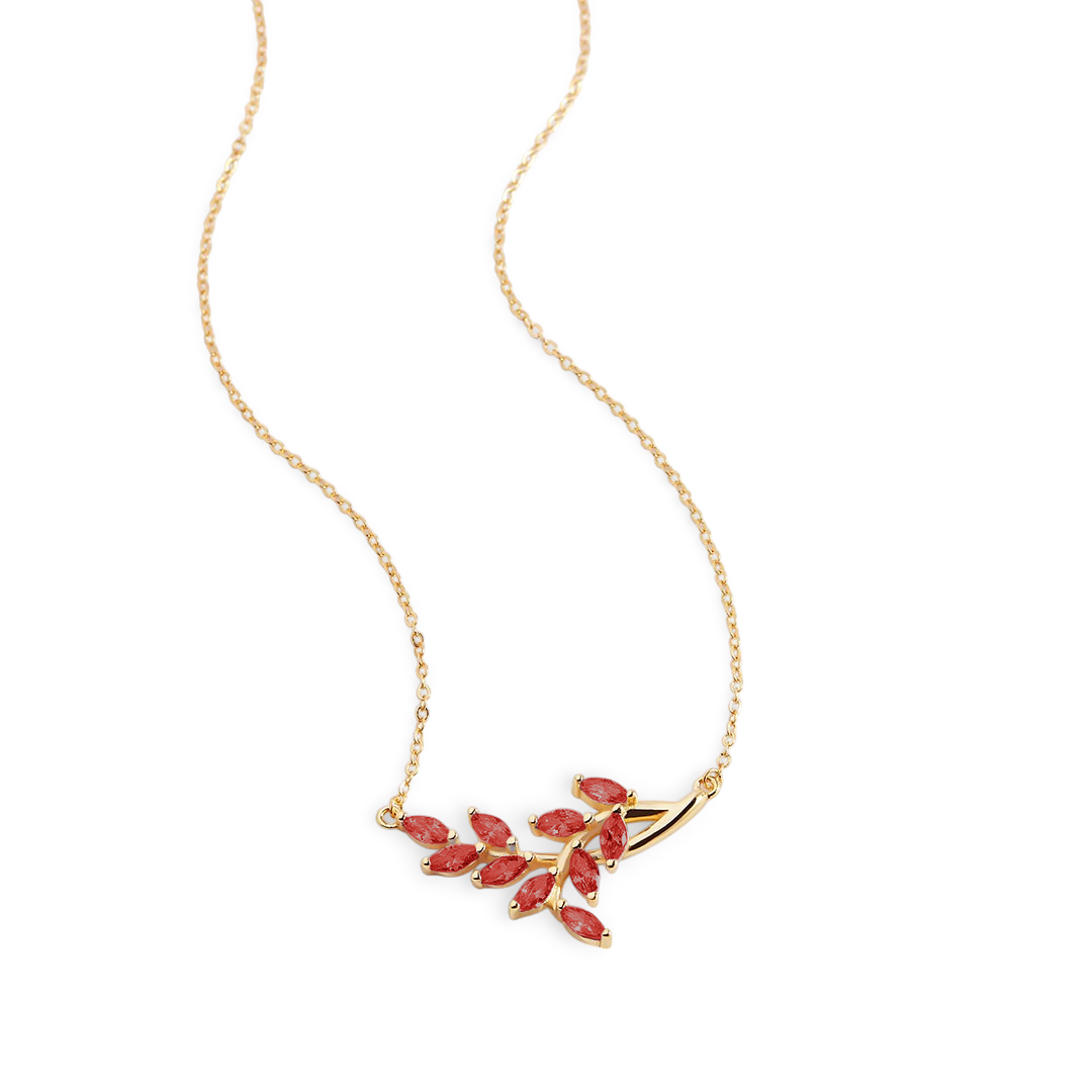 Gold necklace with red gemstones on a light gray background