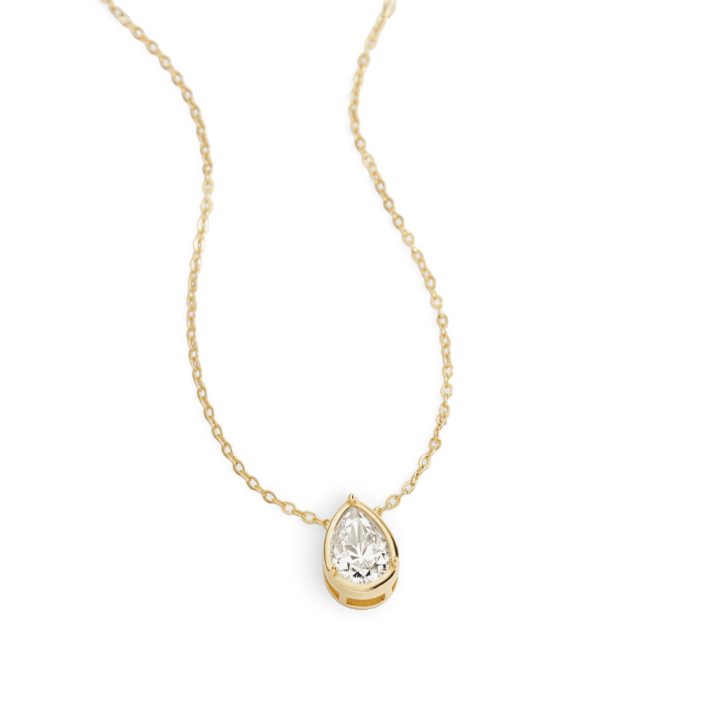 Gold necklace with a teardrop-shaped diamond pendant on a light gray background