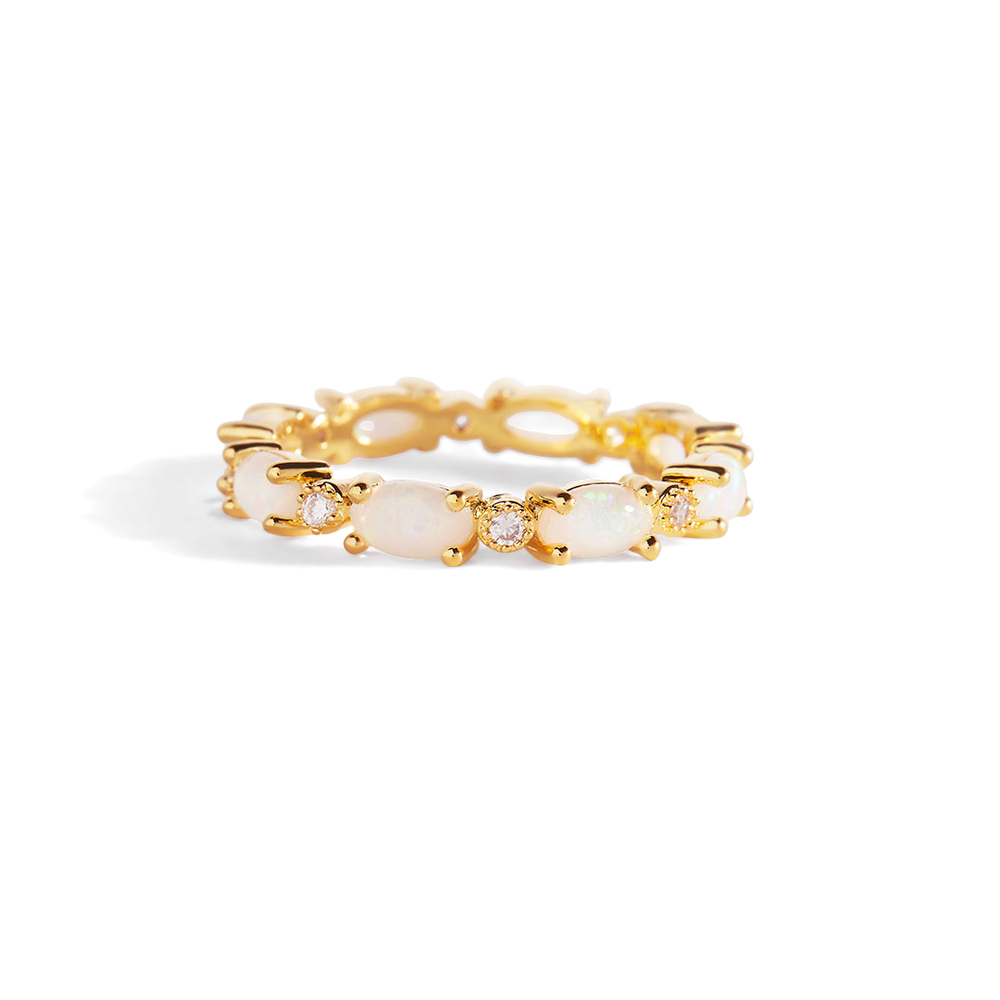 Gold ring with opal stones on a light gray background