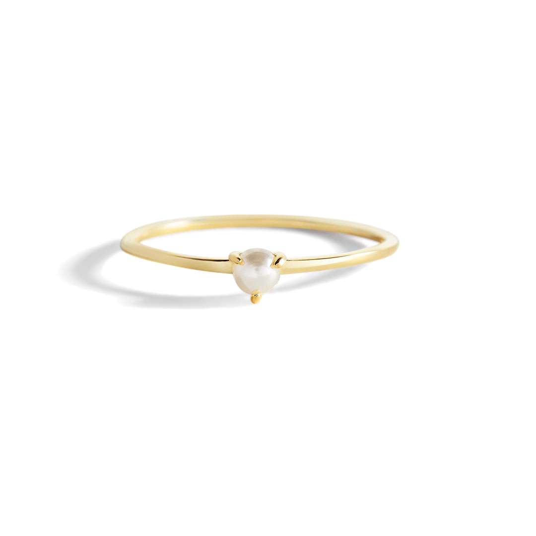 A gold-colored stacking ring with a single freshwater pearl at the top, displayed against a black background.