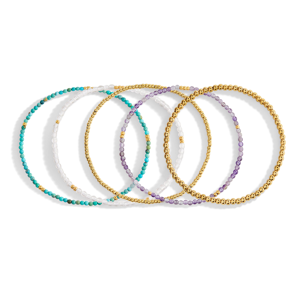 Set of beaded bracelets with gold chain accents on a light gray background