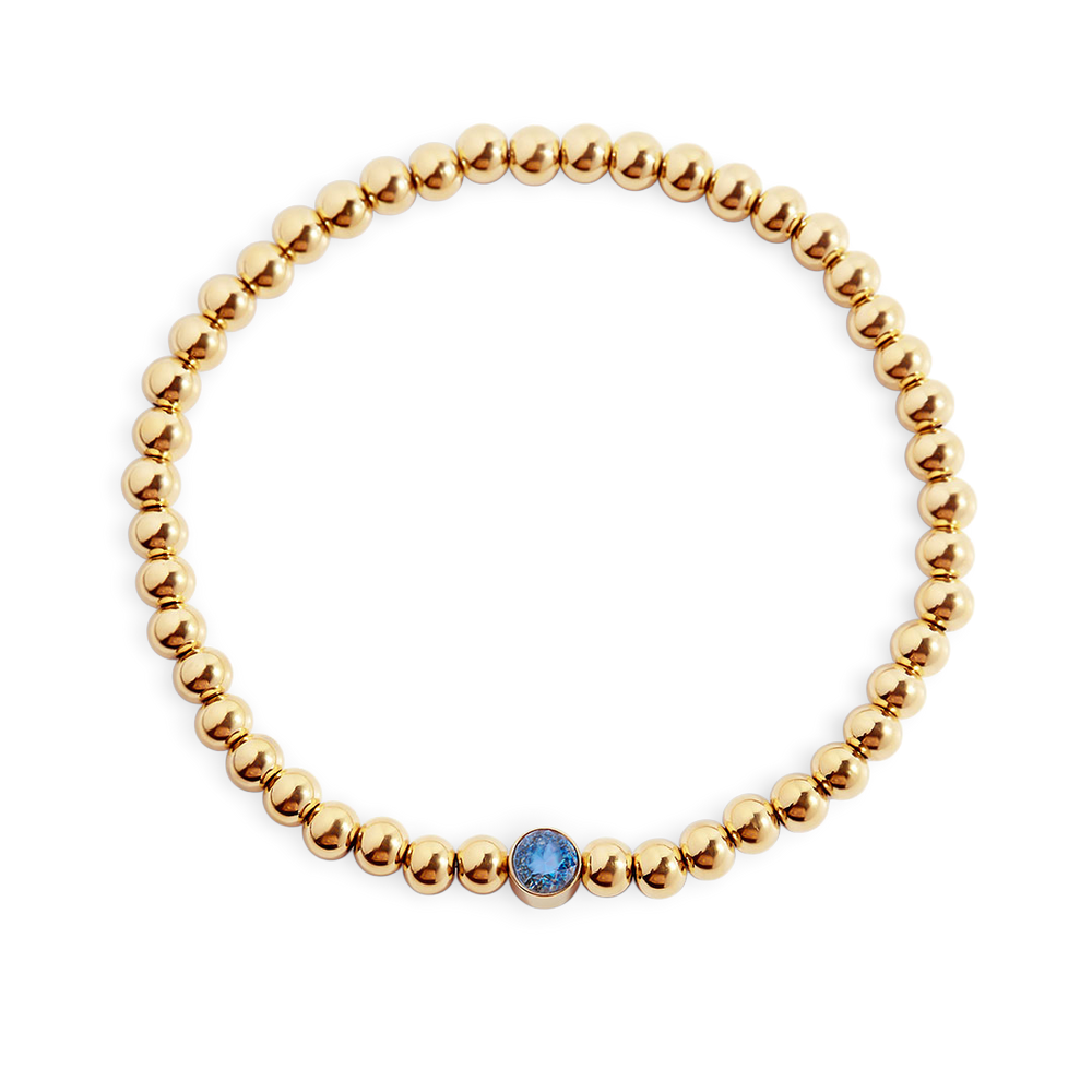 Gold beaded bracelet with a blue gemstone on a light gray background