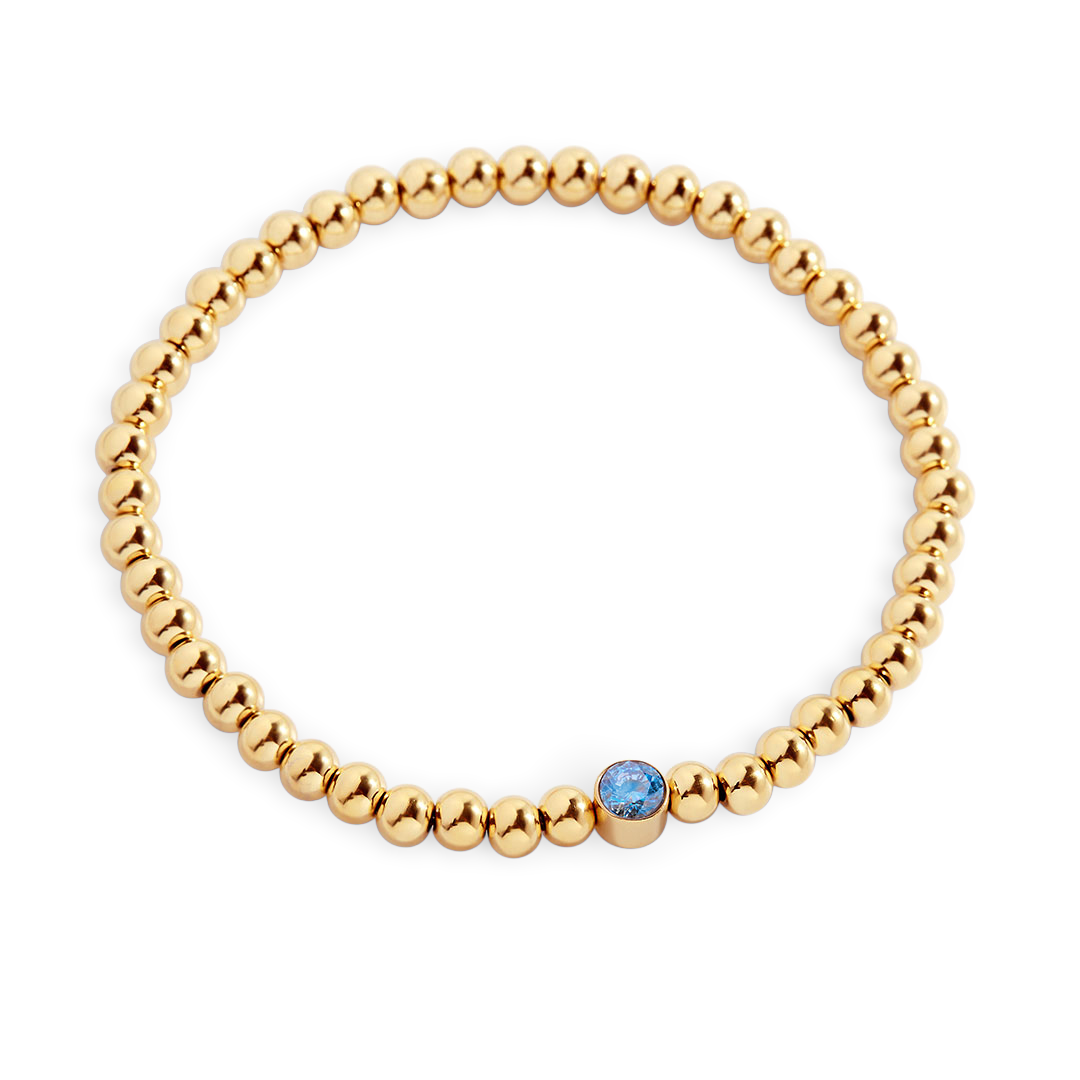 Gold beaded bracelet with a blue gemstone on a white background
