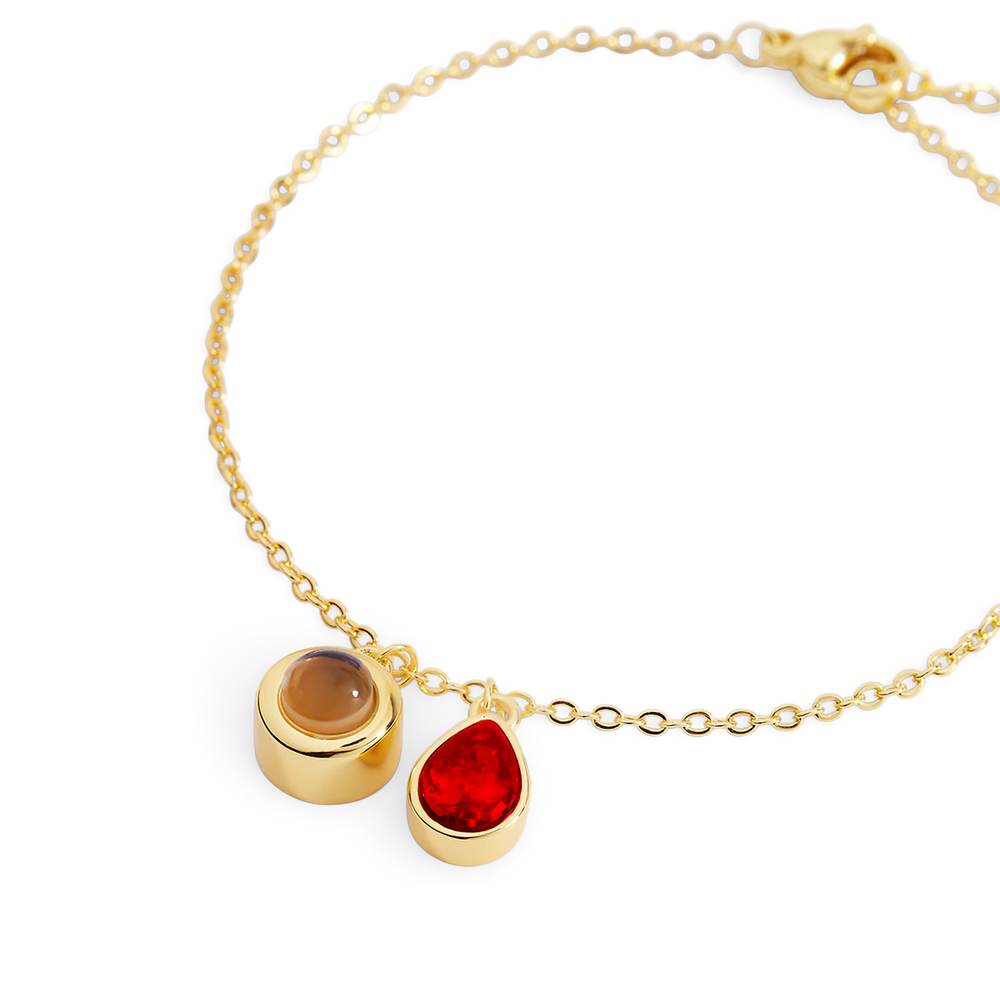 Gold bracelet with two gemstone charms on a white background