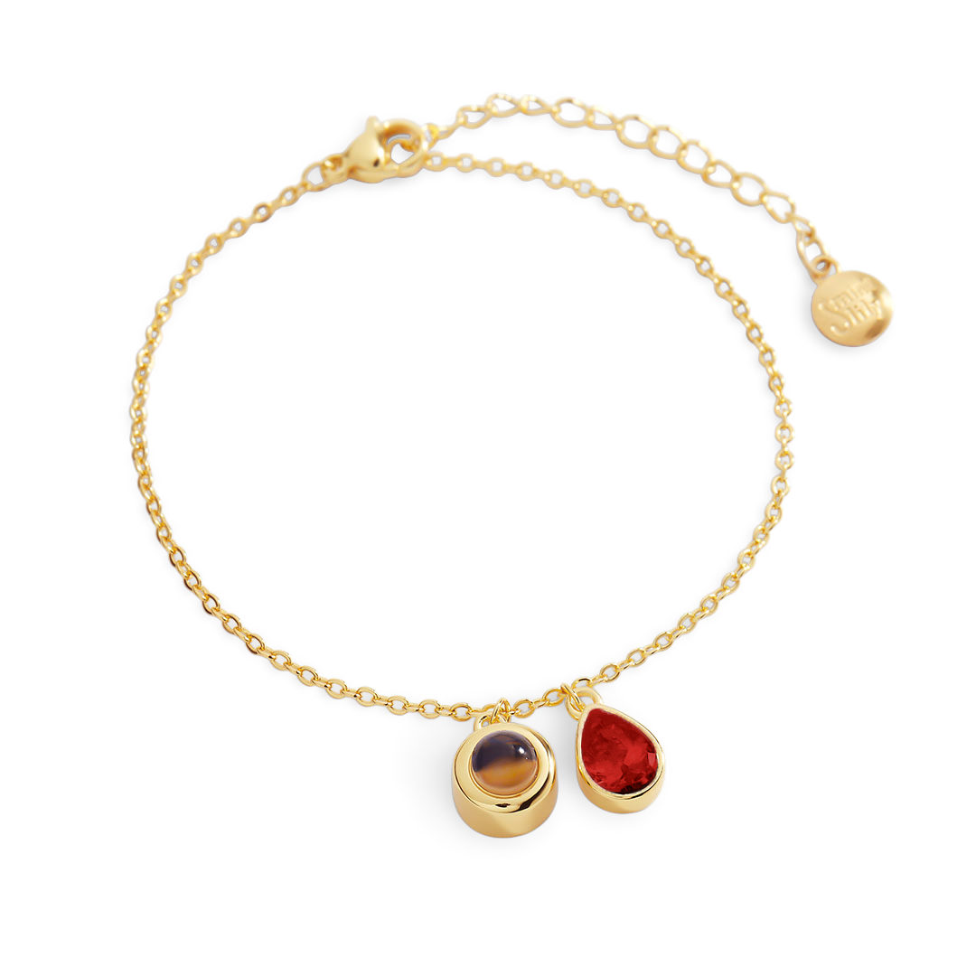 Gold bracelet with three gemstones on a white background