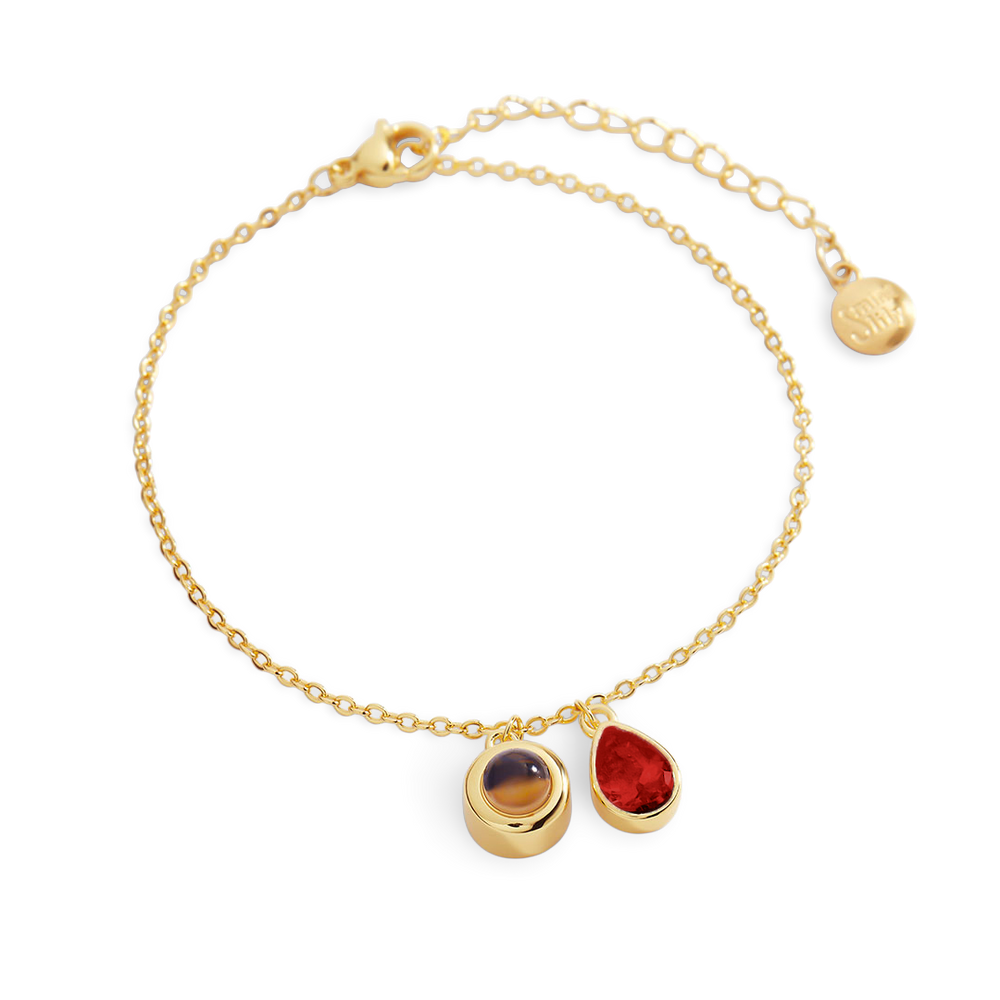 Gold bracelet with three gemstones on a white background