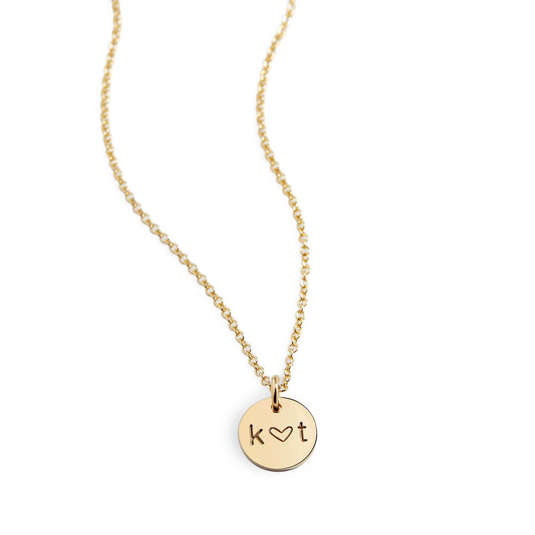 A gold-plated necklace with a circular pendant featuring the initial 'K'.