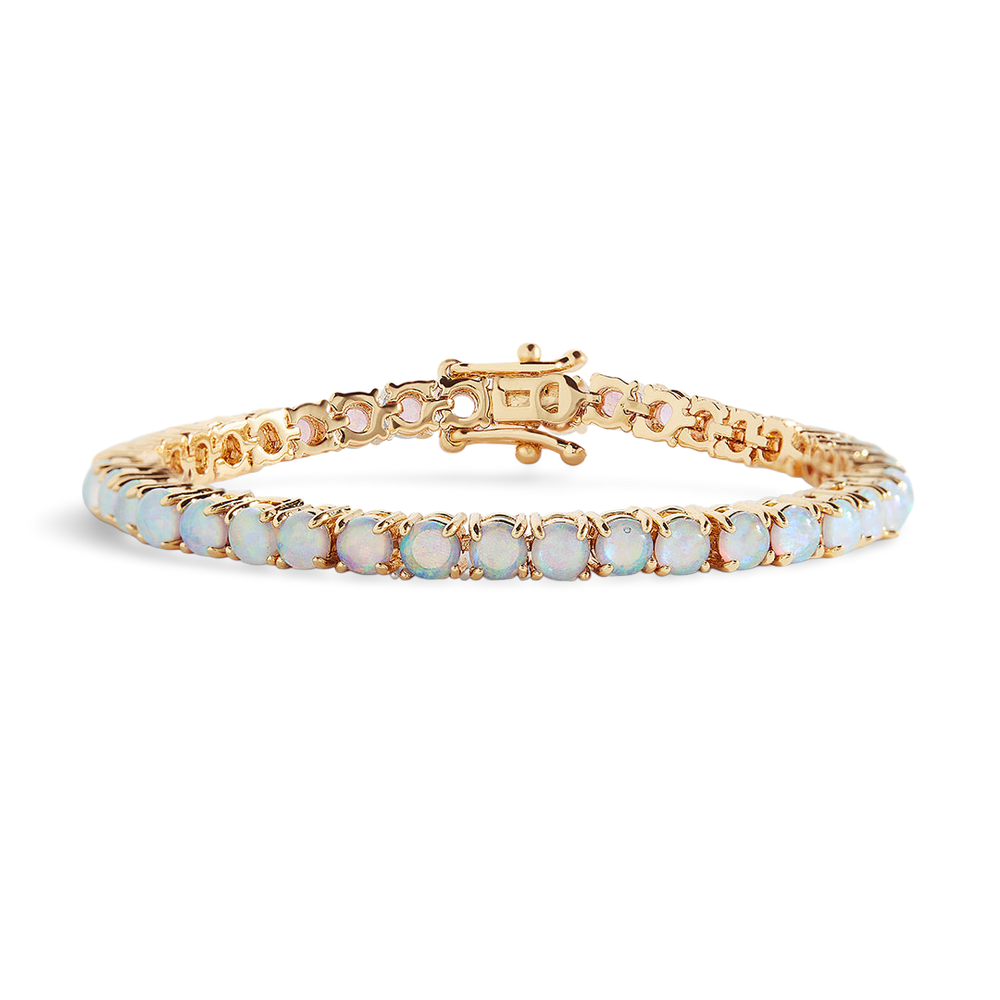 Gold bracelet with white stones on a light gray background