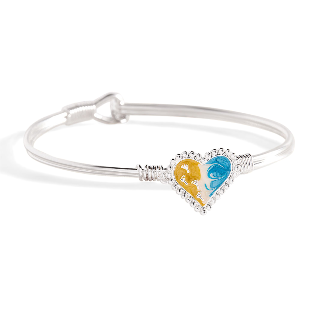 Silver bracelet with a heart-shaped charm featuring a yellow and blue design on a white background