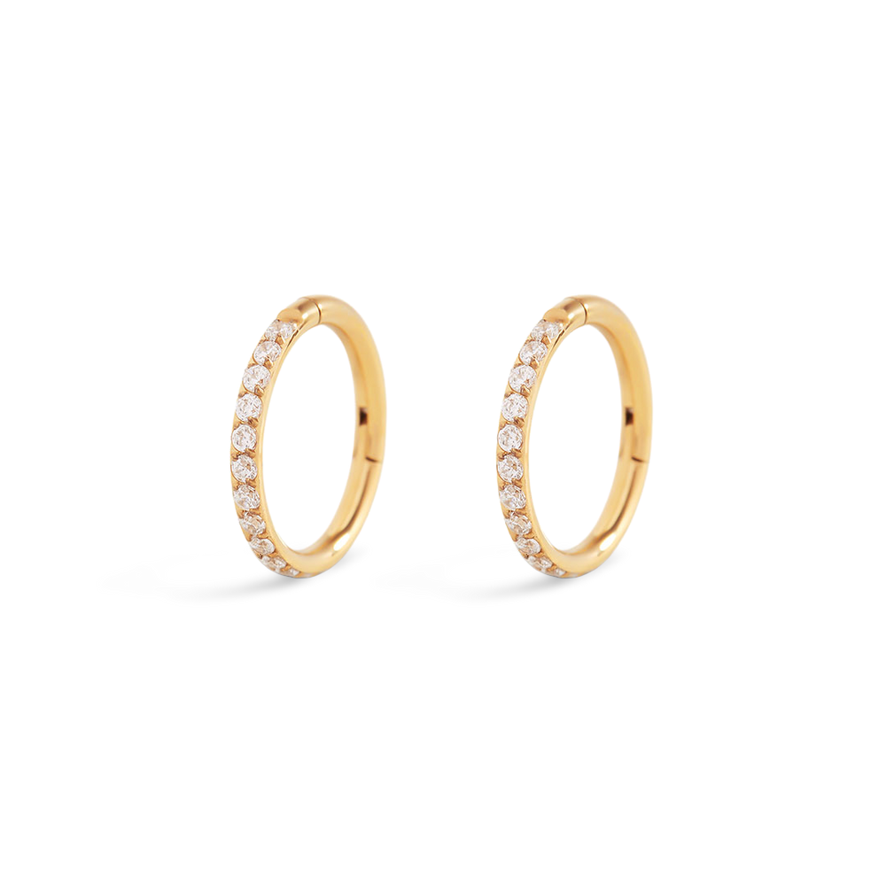 Pair of gold hoop earrings with embedded diamonds on a light gray background