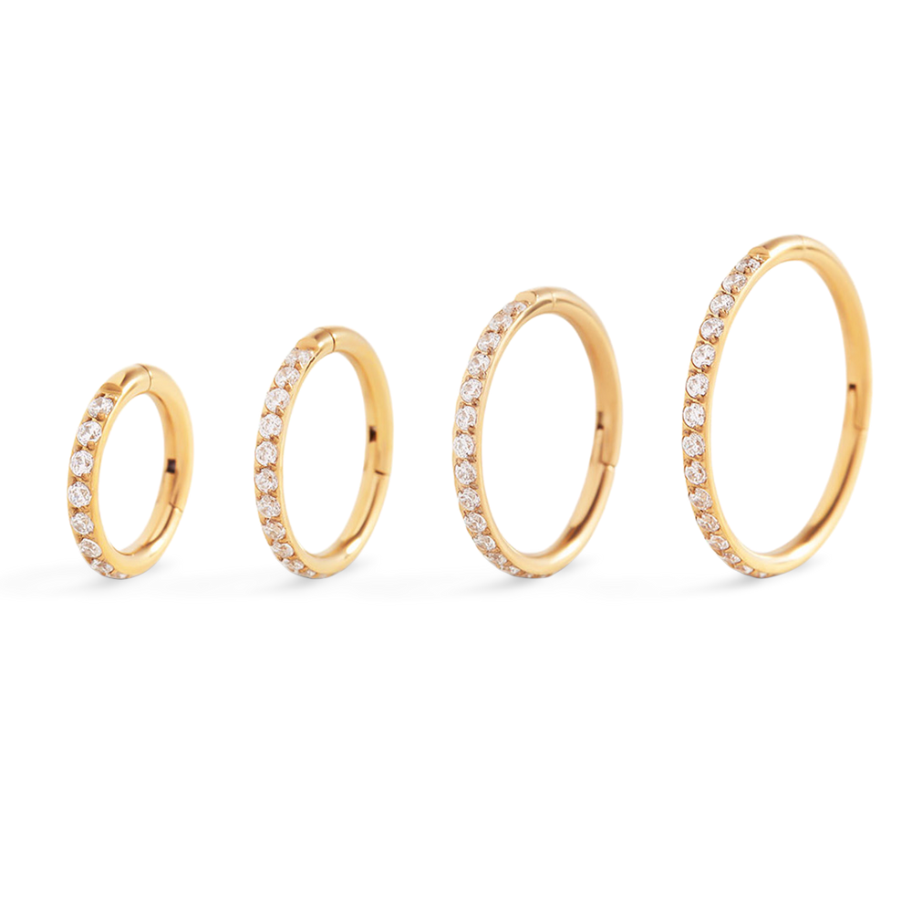 Set of four gold rings with diamond accents on a light gray background