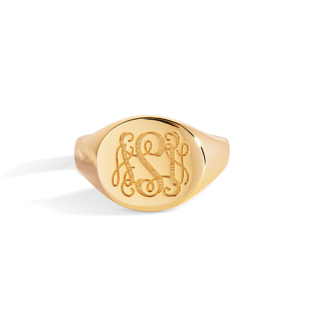 Gold ring with engraved initials on a light gray background