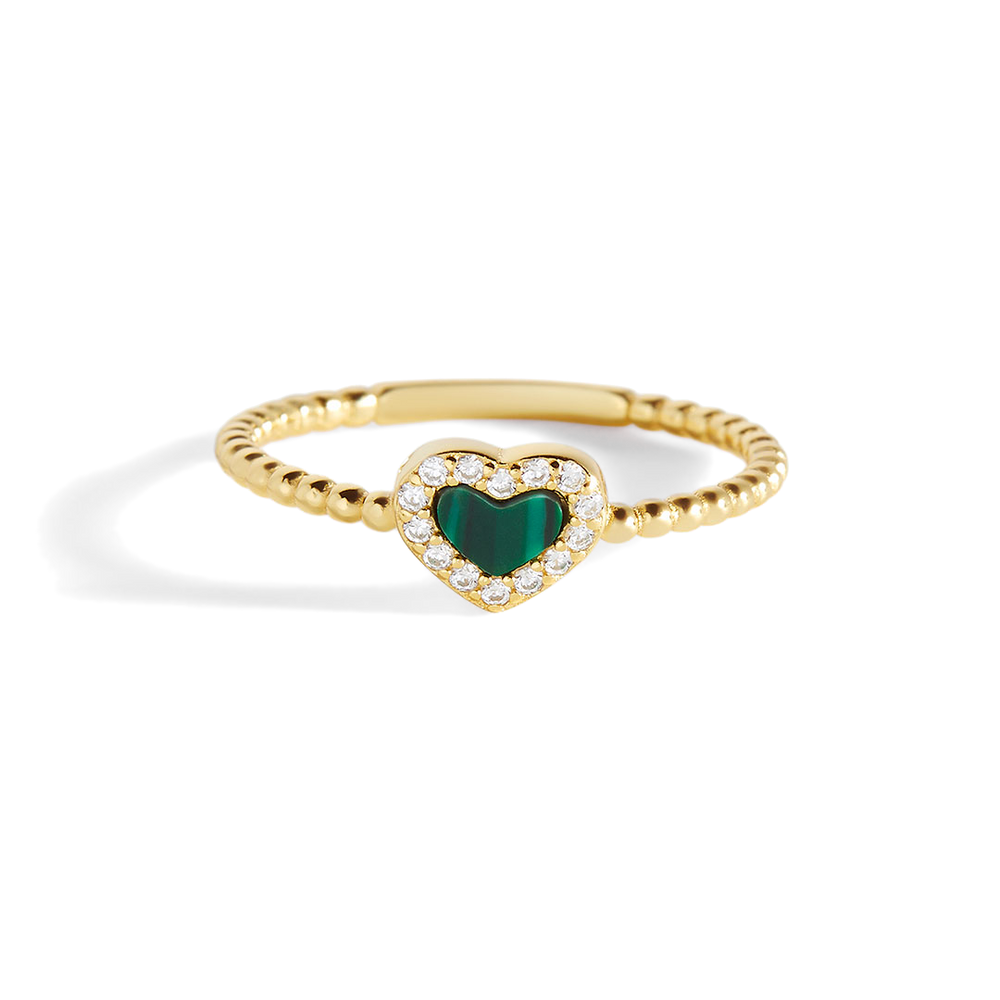 A gold-colored band ring with a heart-shaped blue gemstone in the center, surrounded by smaller clear gems, against a black background.