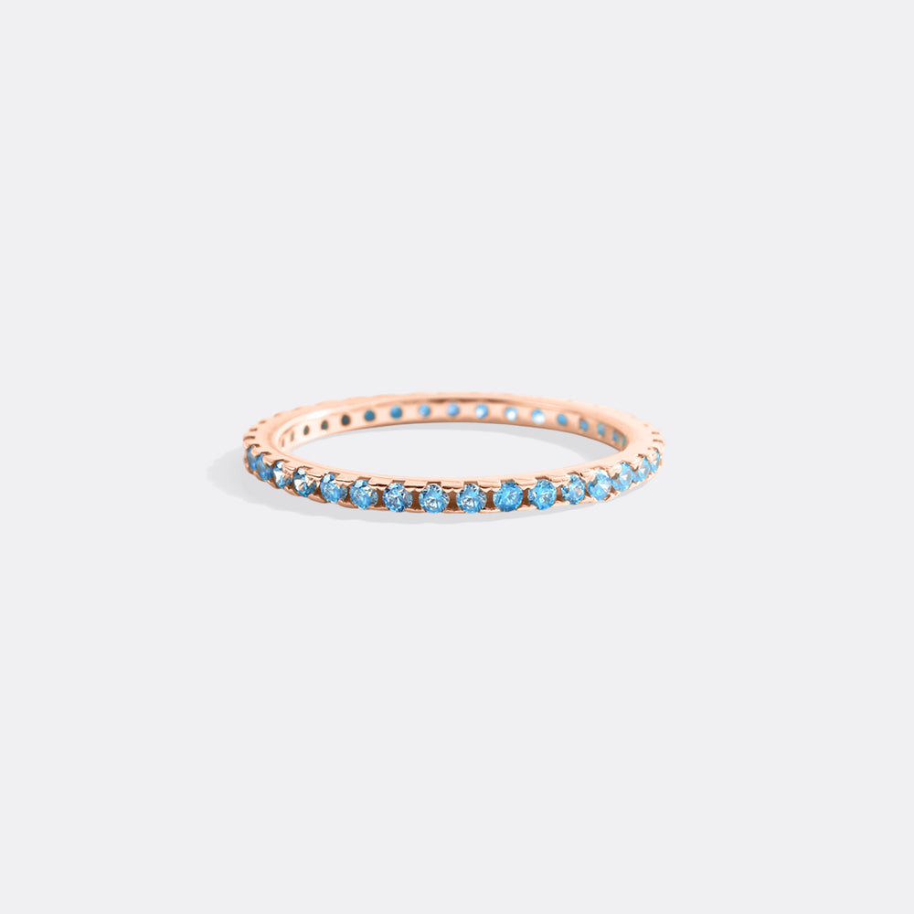 Rose gold ring with blue gemstones on a light gray background