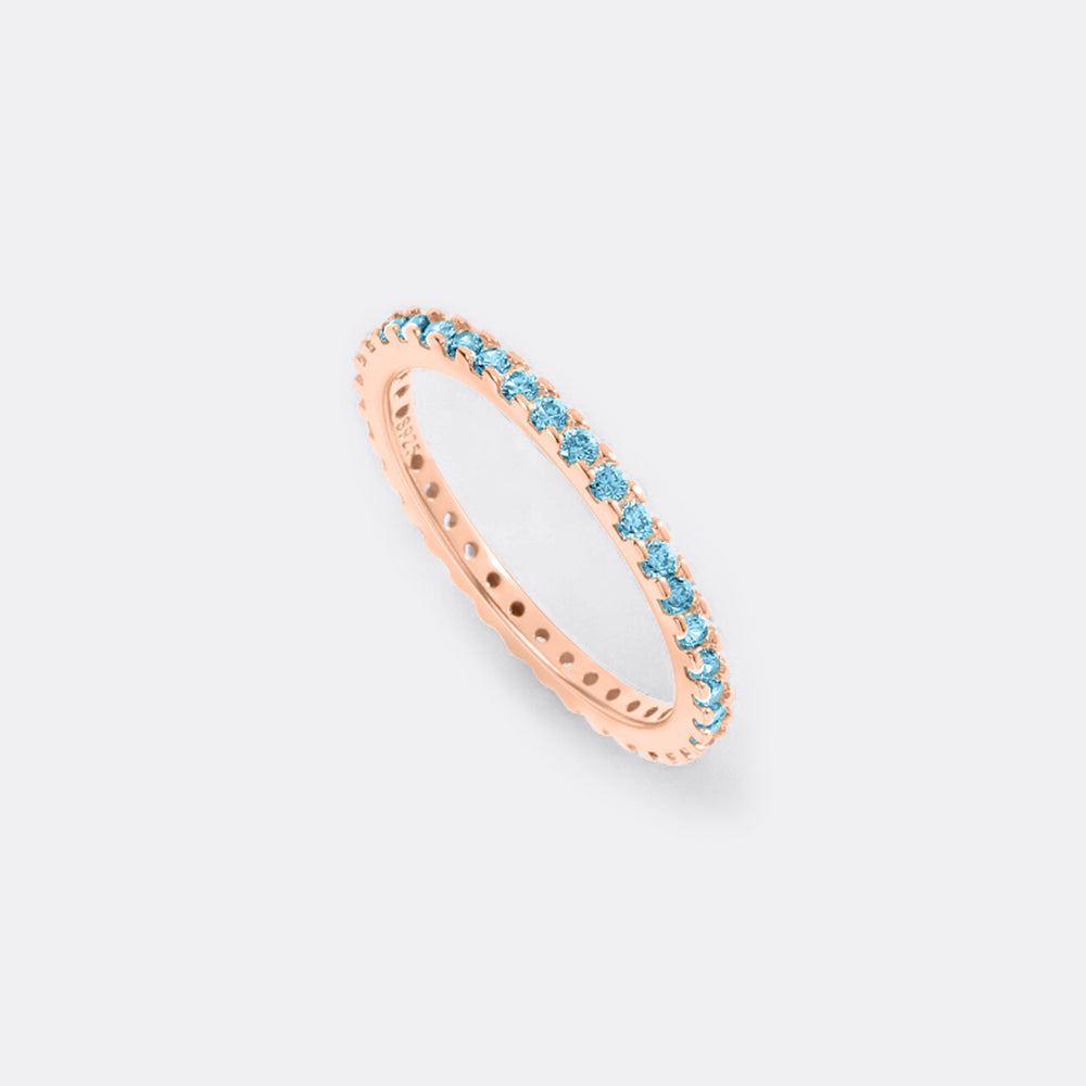 Rose gold ring with blue gemstones on a light gray background