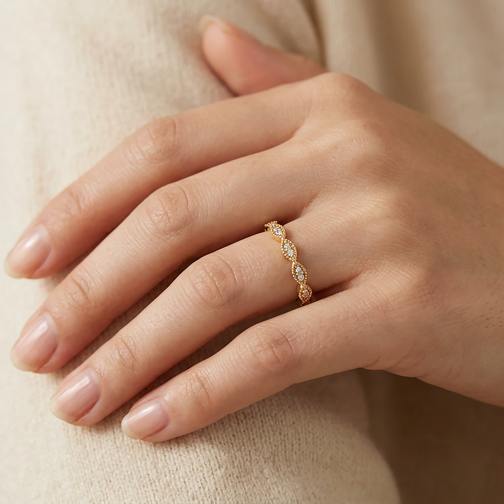Gold ring with small diamonds on a hand against a beige background
