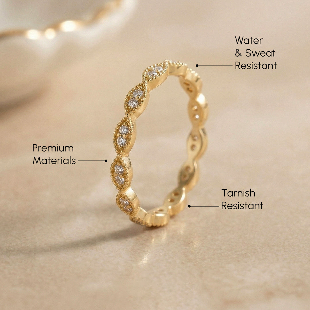 Gold ring with diamond accents on a beige background, labeled for water & sweat resistance, premium materials, and tarnish resistance.