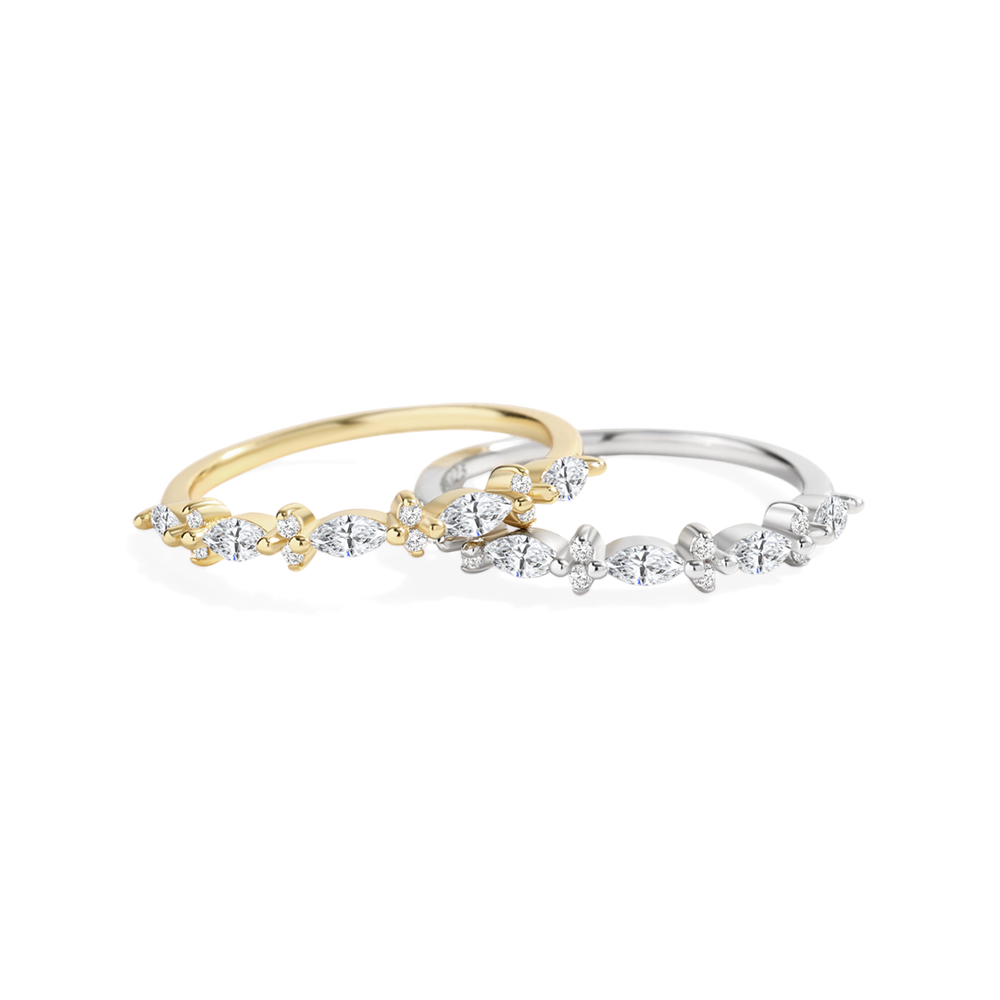 Two diamond-studded rings, one gold and one silver, on a light gray background.