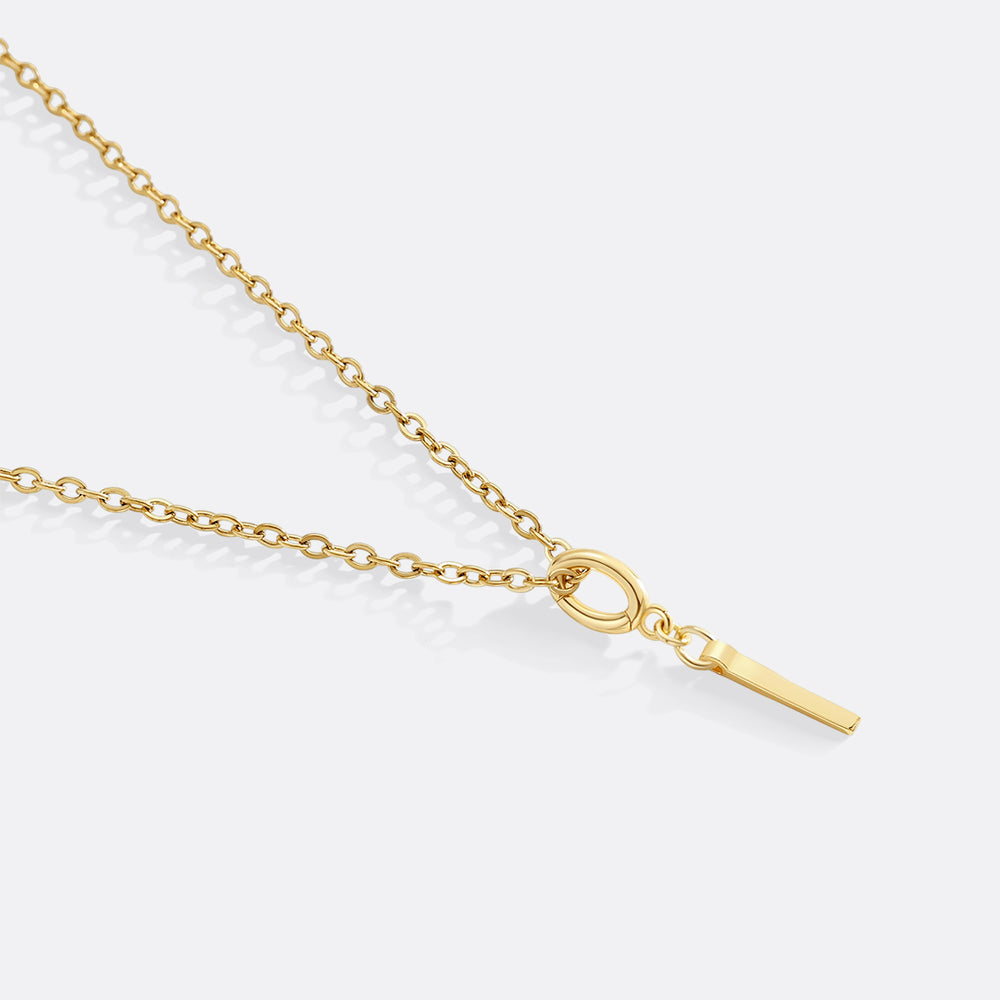 Gold necklace with a small pendant on a light gray background