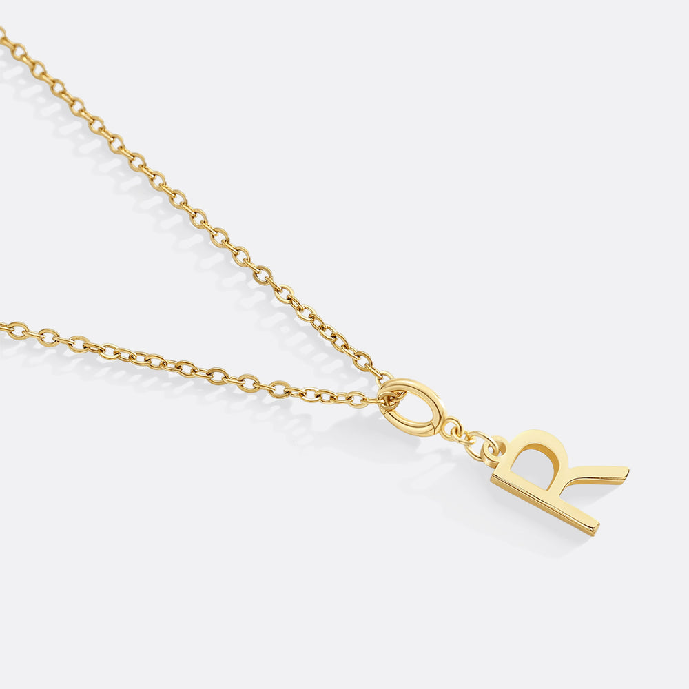 Gold necklace with a 'R' pendant on a white background