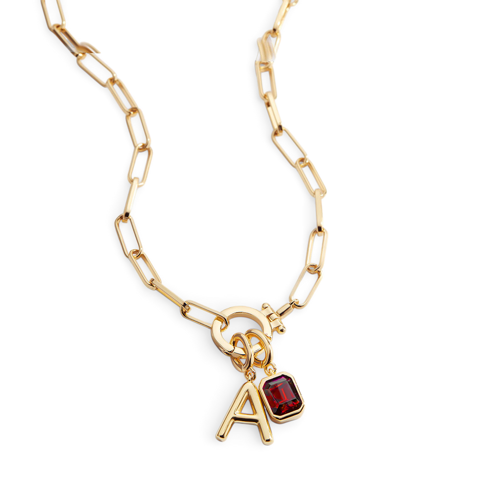 Gold necklace with a red gemstone and letter 'A' charm on a white background