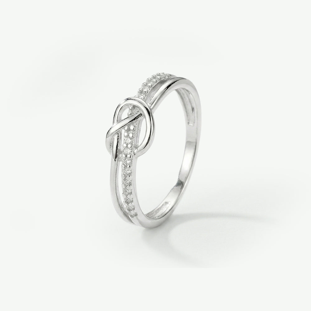 Silver ring with diamond accents on a light gray background