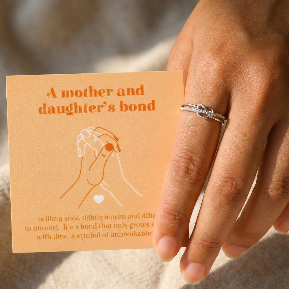 Hand wearing a silver ring with a card about a mother and daughter's bond