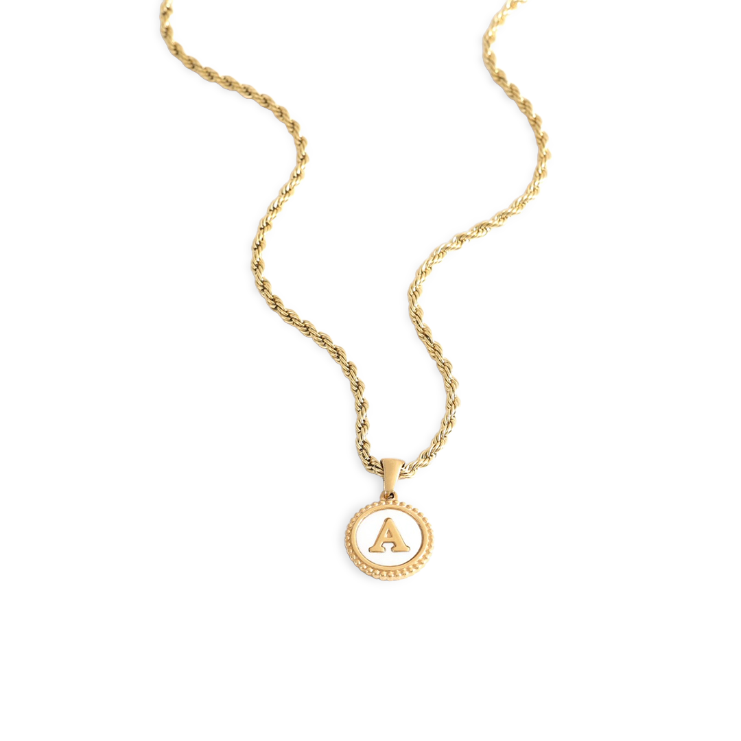 A gold rope chain necklace with a mother of pearl disc pendant engraved with a letter.