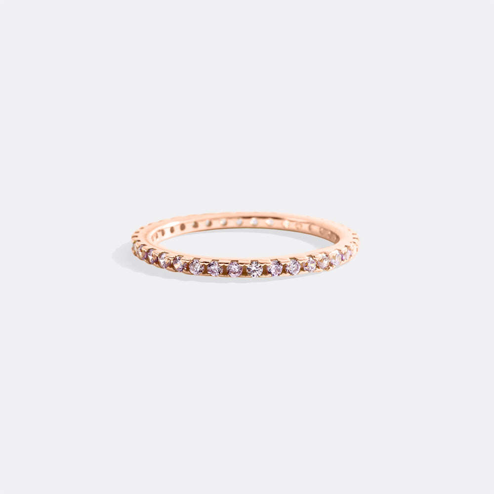 Rose gold ring with small diamonds on a light gray background