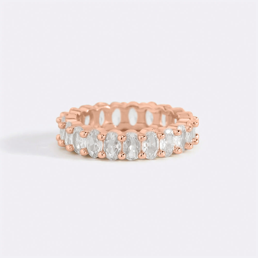A gold-colored eternity ring with oval-shaped stones set around its entire circumference.