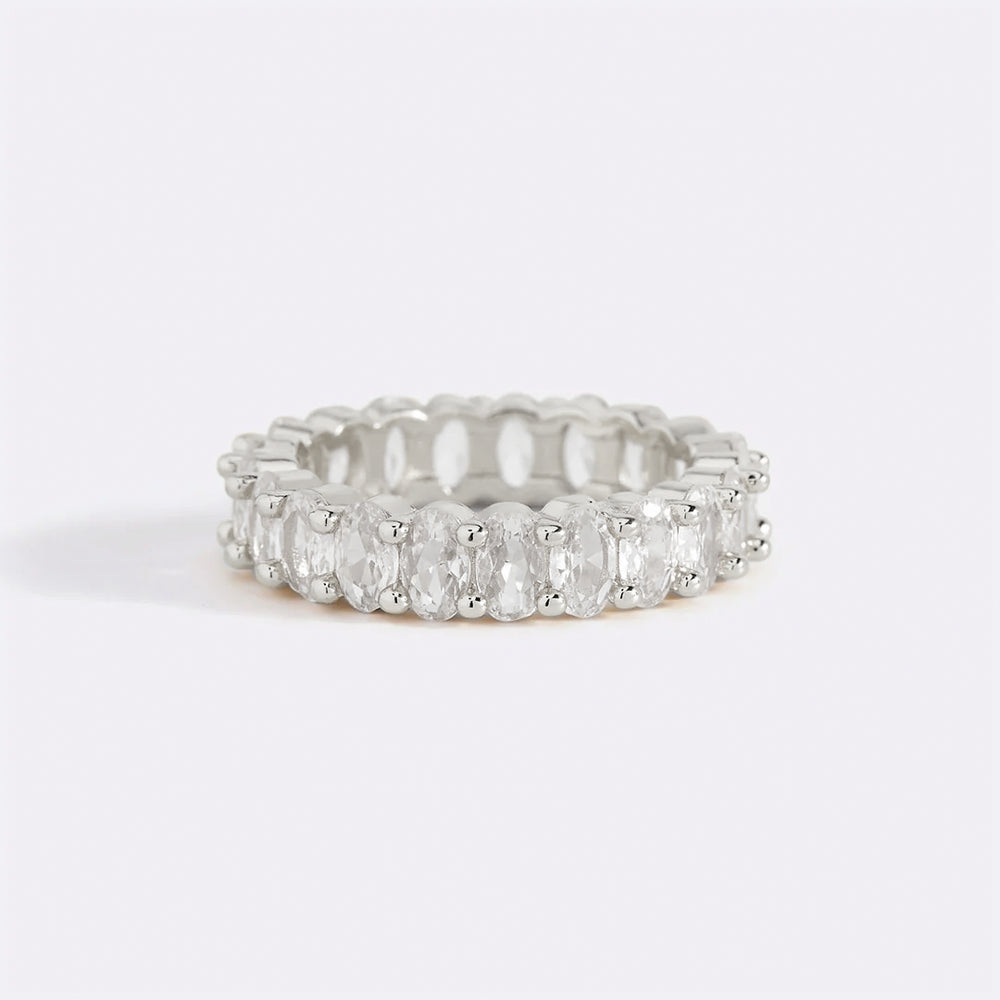 A gold-colored eternity ring with oval-shaped stones set around its entire circumference.