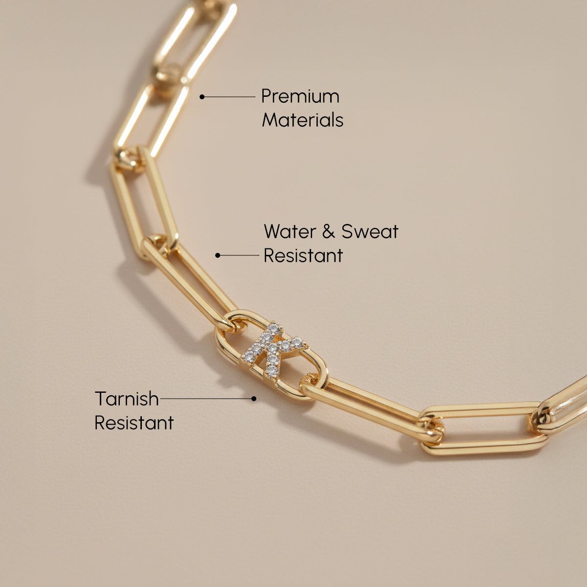 Gold chain bracelet with text highlighting features on a beige background