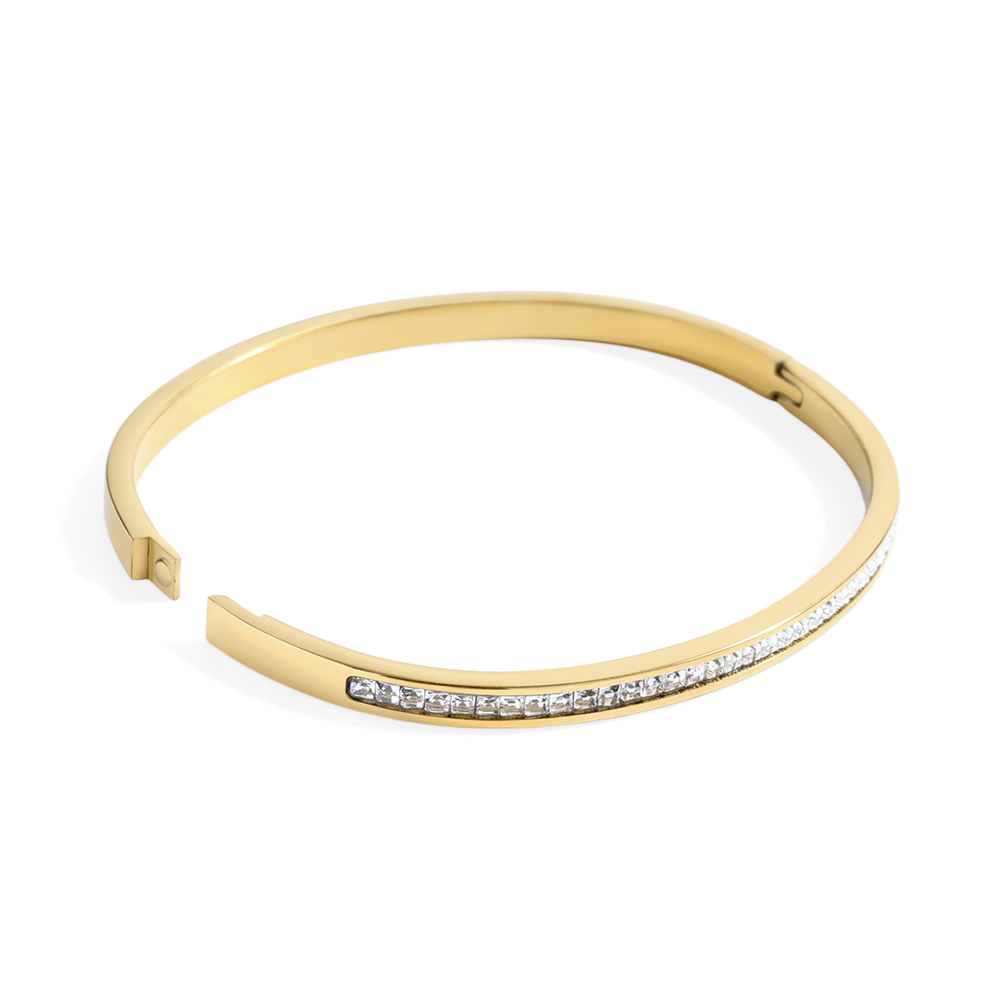 Gold bracelet with small diamonds on a light gray background