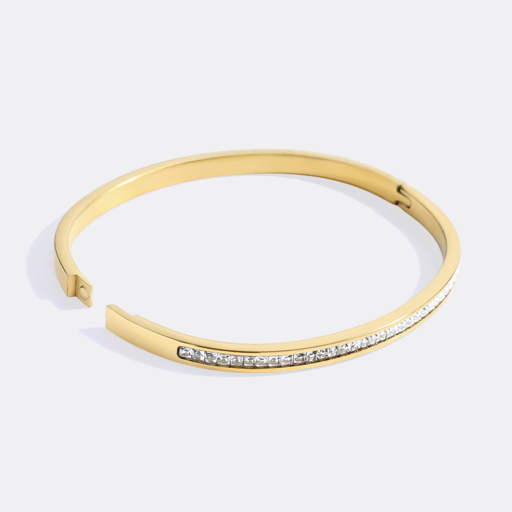 Gold bracelet with small diamonds on a light gray background