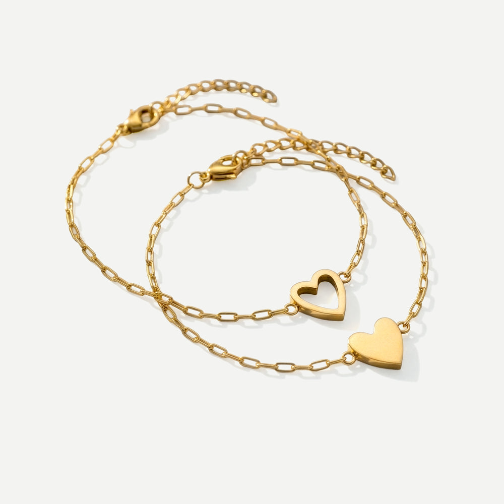 Two gold heart-shaped necklaces on a white background