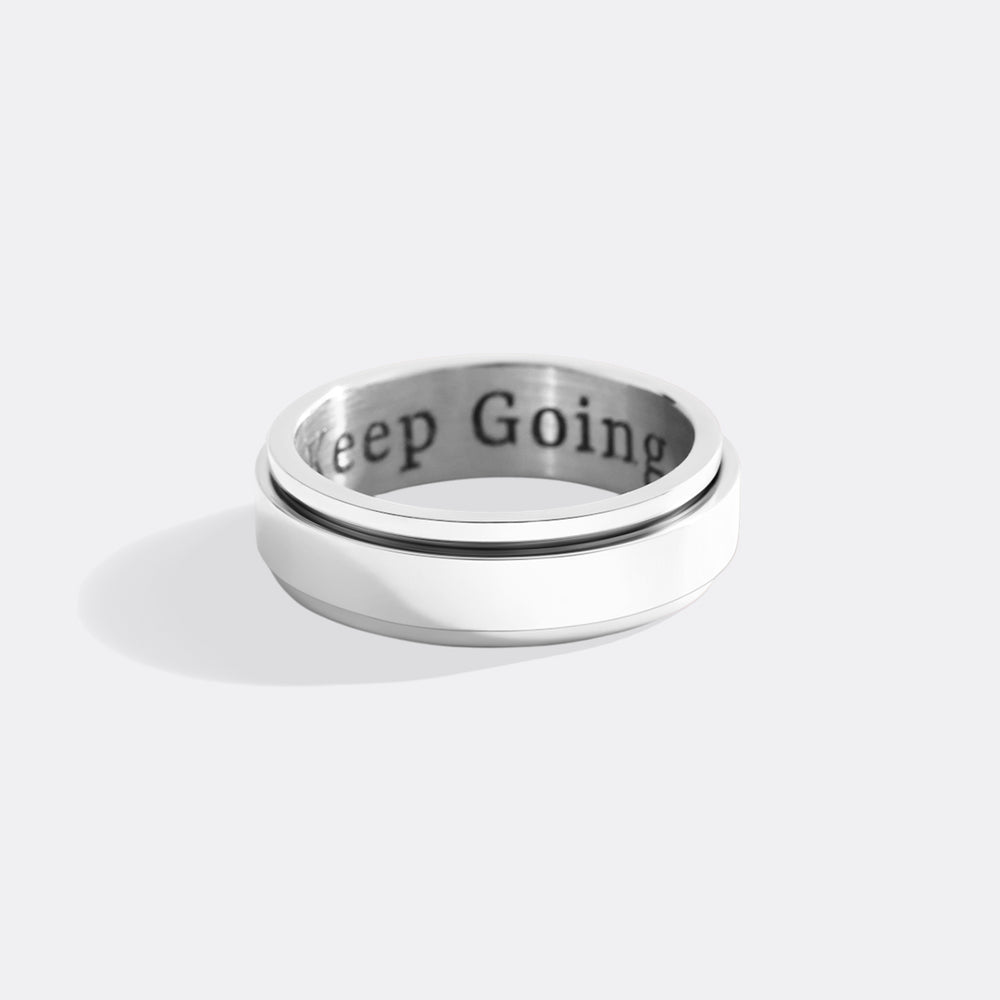 Silver ring with 'Keep Going' engraving on a white background