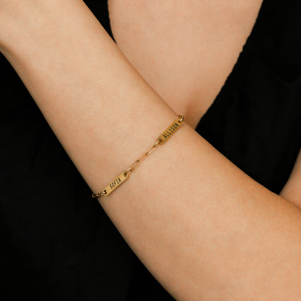 Gold bracelet on a person's wrist against a black background