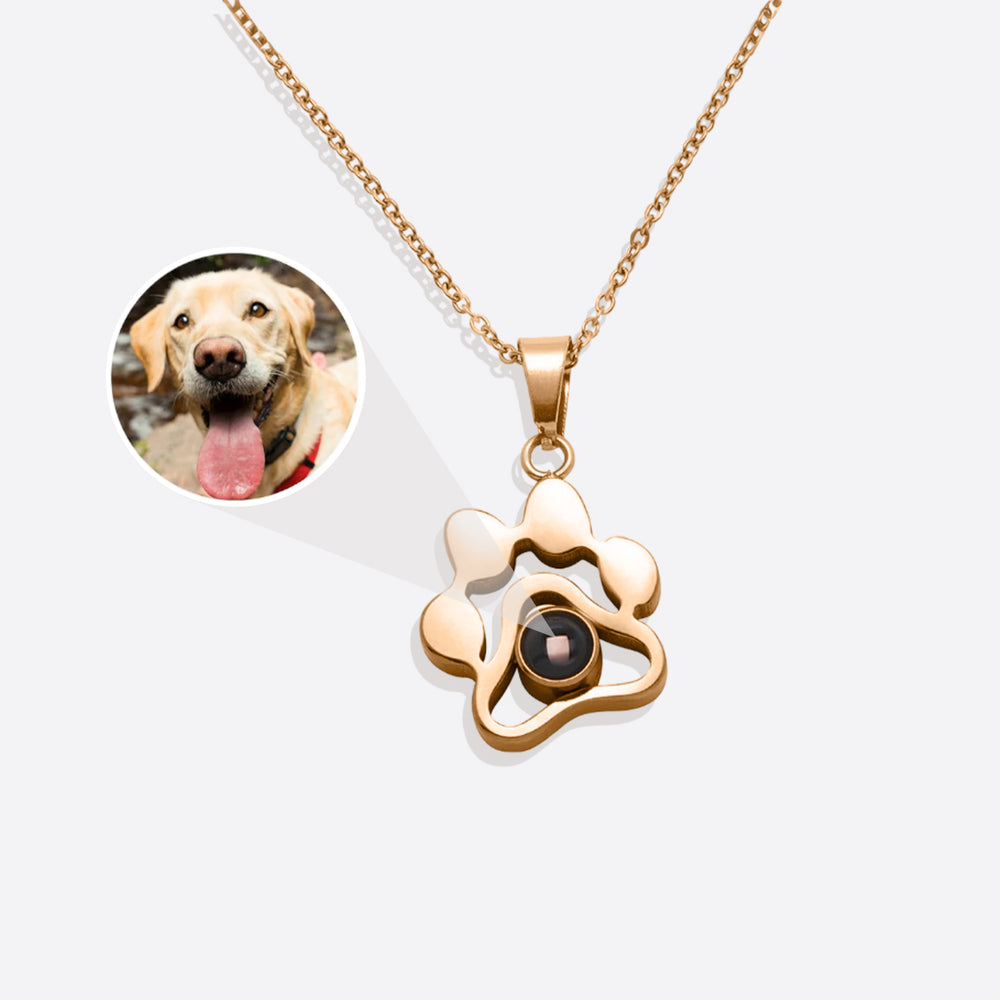 A personalized pet photo necklace with a gold-colored chain and a paw-shaped charm containing a photo of a dog.