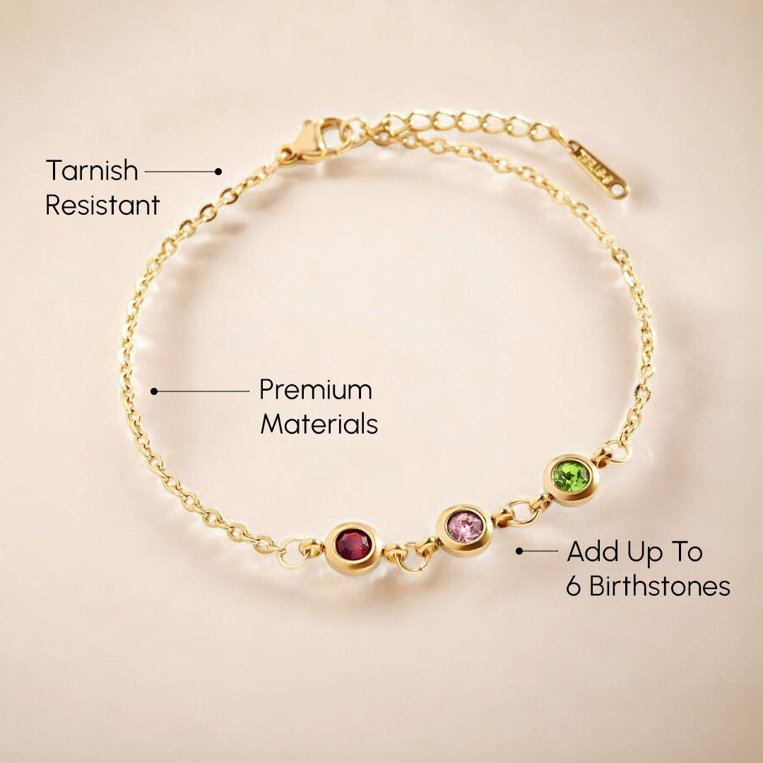 Gold bracelet with birthstones on a beige background