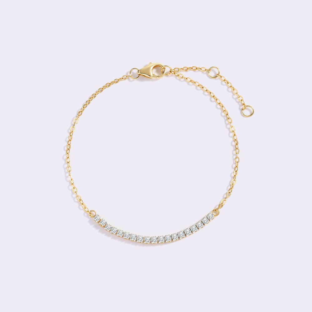 Gold petite line bracelet with a row of sparkling stones on a fine cable chain, arranged in an open loop on a light background.