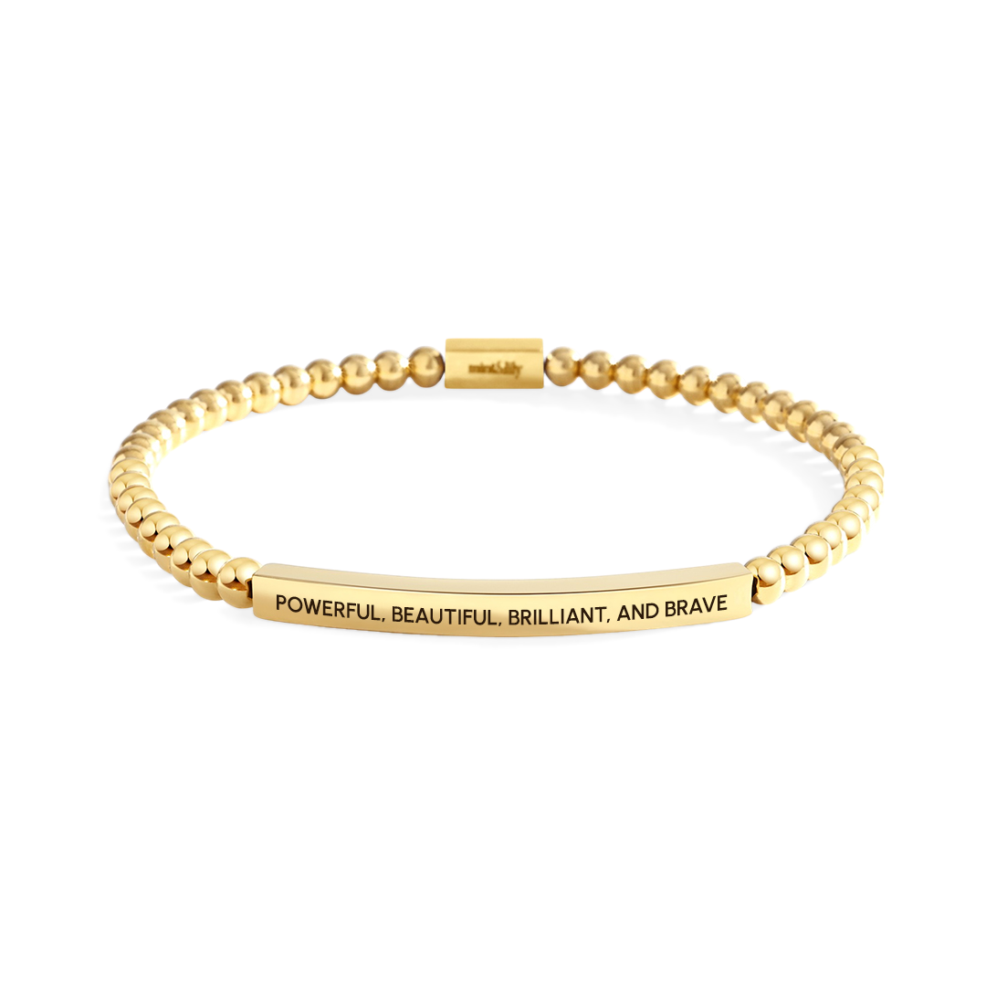 Gold bracelet with engraved message on a white background
