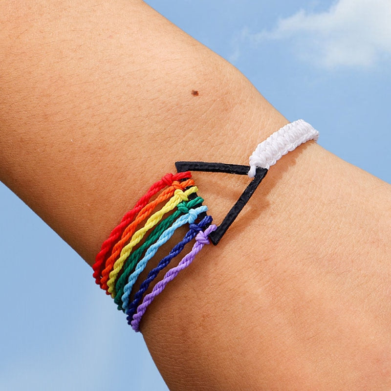 A multicolored rope bracelet with a geometric prism design, displayed on a person's wrist against a blue sky background.