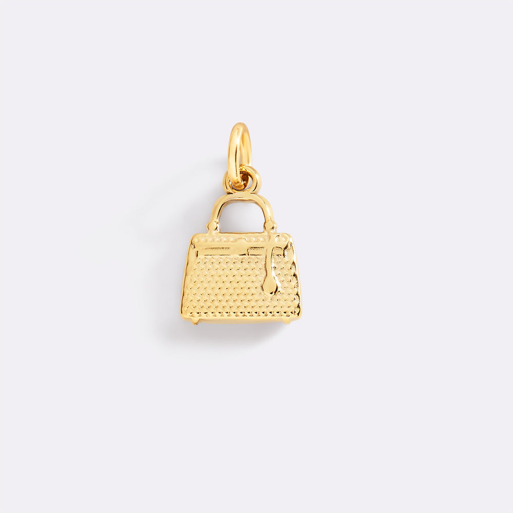 Gold handbag charm on a light gray background