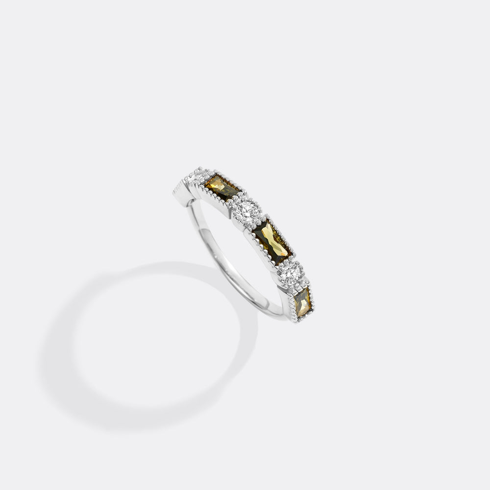 Silver ring with embedded stones on a light gray background