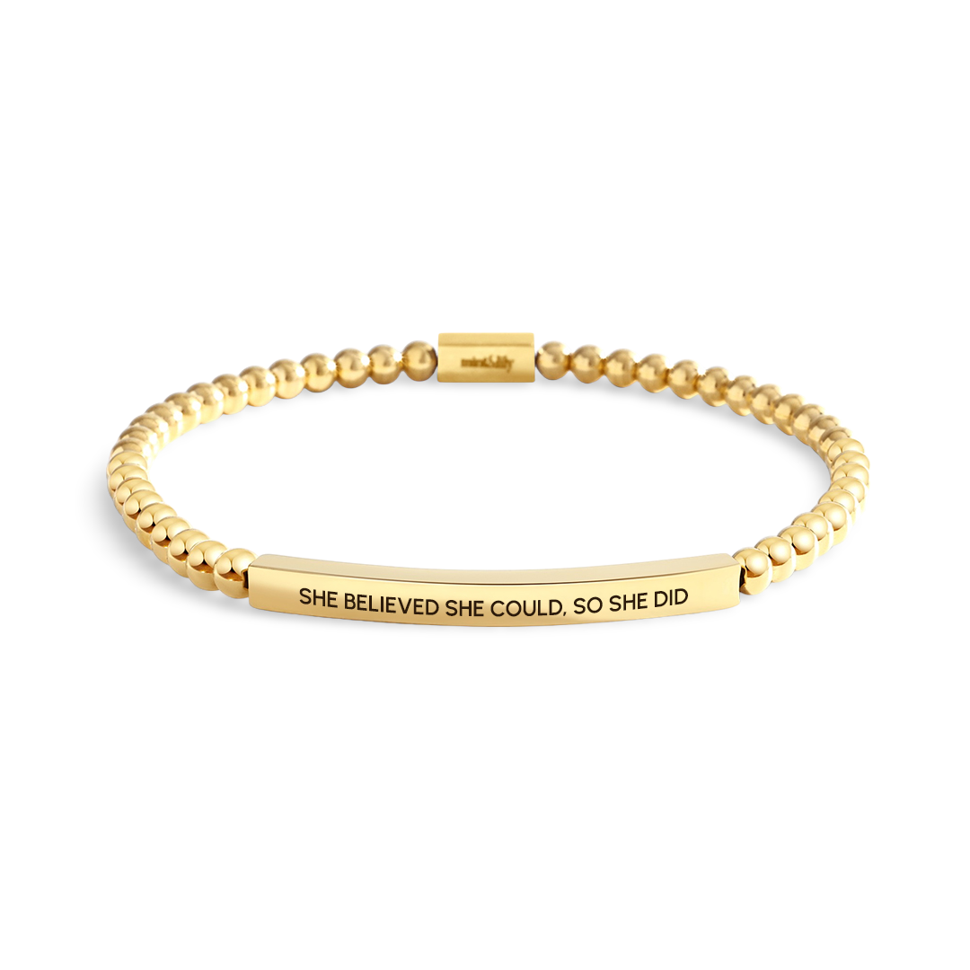 Gold bracelet with motivational quote on a white background