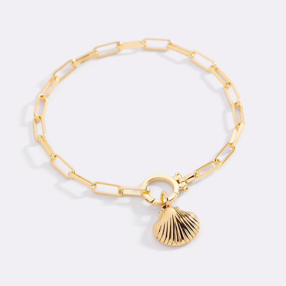 Gold bracelet with a shell charm on a light gray background
