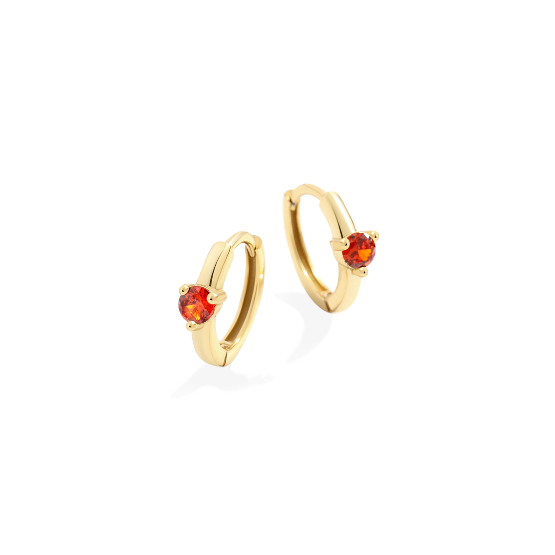 Gold hoop earrings with red gemstones on a white background