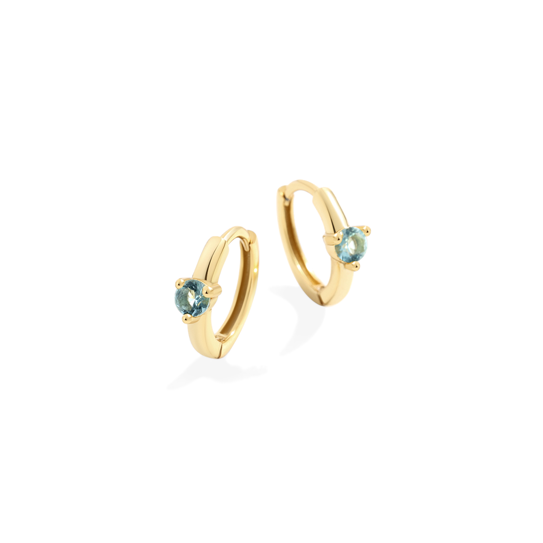 Gold hoop earrings with blue gemstones on a white background