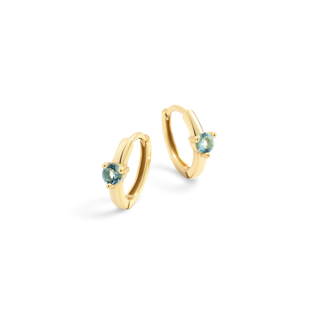 Gold hoop earrings with blue gemstones on a white background